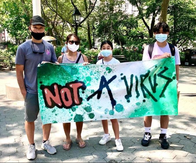 Children protesting anti-Asian hate hold a Not a Virus banner while marching through New York City