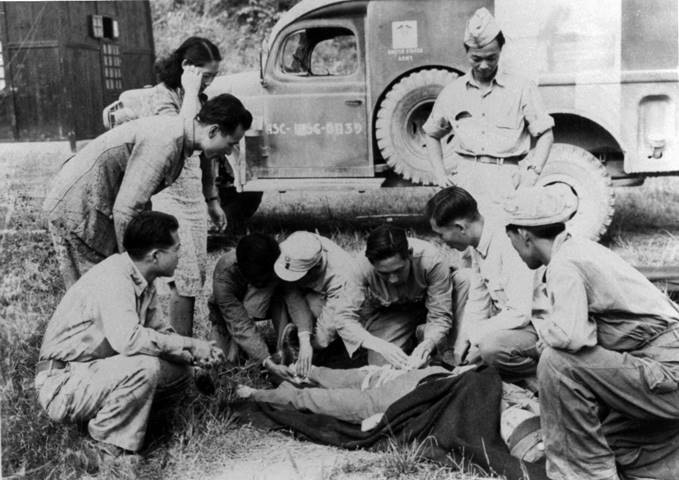    Dr. Julius Sue treating a wounded solider at an airfield in China