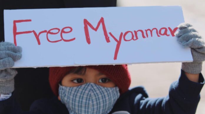 child holds up Free Myanmar sign