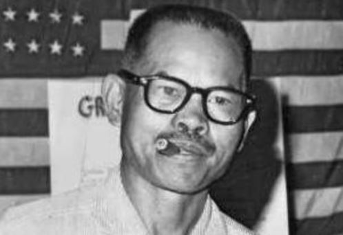 Photo of Larry Itliong with what looks like a cigar between his lips.