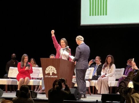 Sheng Thao raises her arms in victory following her swearing in