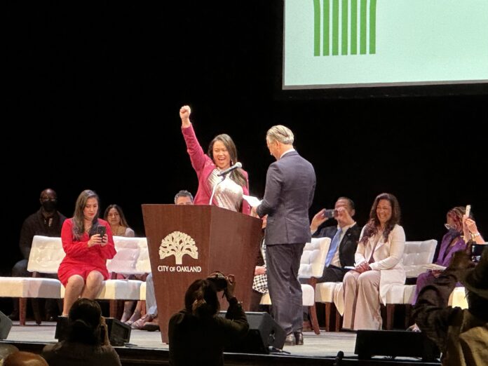 Sheng Thao raises her arms in victory following her swearing in