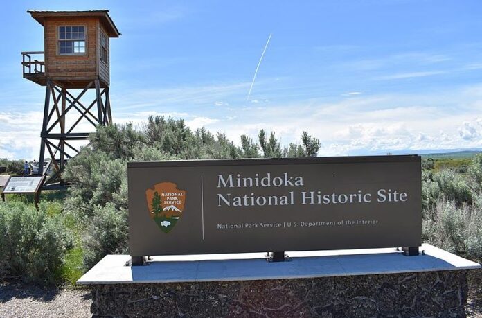 The sign in the foreground identifies Minidoka National Historic Site with a guard tower in the background