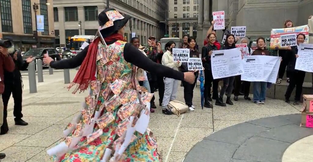 A dress made of postcards opposing the Philadelphia 76er arena is modeled by a demonstrator to the cheers of fellow protestors 