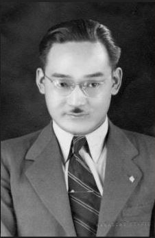 Photo of Minori Yasui with mustache, tie and wearing a suit jacket