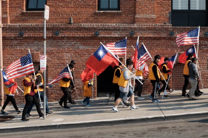 Asian Americans march with American flagas with one holding a flag from Taiwan