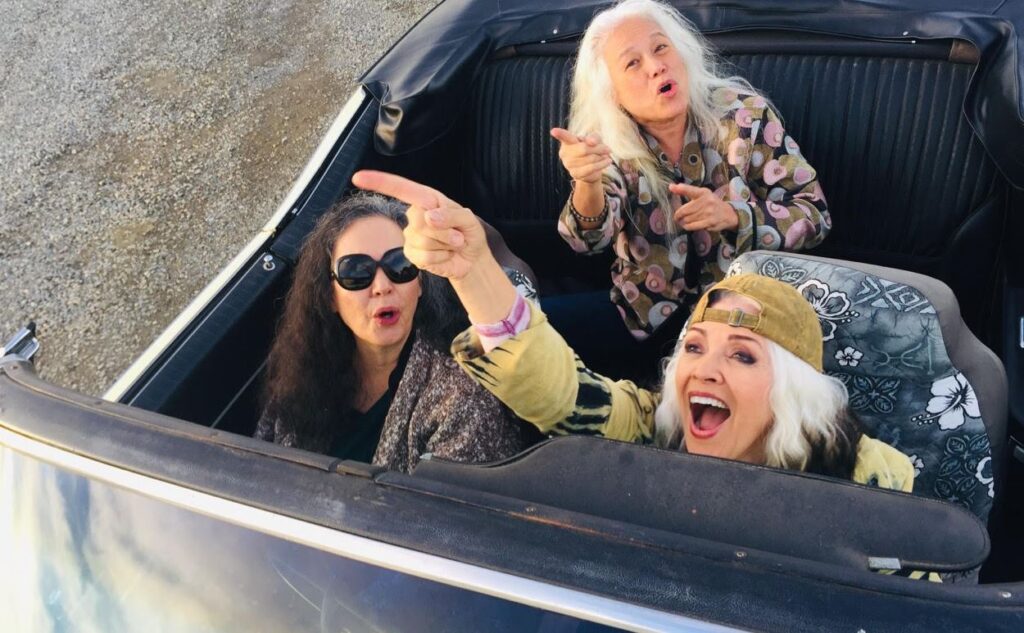 LtoR – Fanny bassist Jean Millington, Fanny lead guitarist June Millington, Fanny drummer Brie Darling, riding in a convertible in California after the release of their new album Fanny Walked the Earth.  