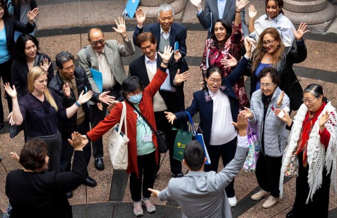 Woori Juntos organizing and policy manager Steven Wu, front center, leads a chant with staff and supporters after a public hearing Tuesday for HB 5166.