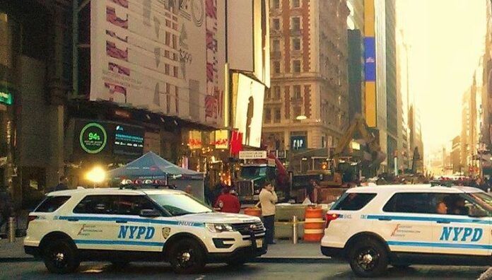 Two NYPD vehicles in New York with electronic billboard in the background