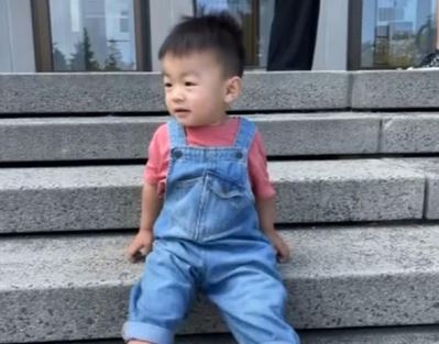 Jasper Wu is seen in overalls sitting on the steps