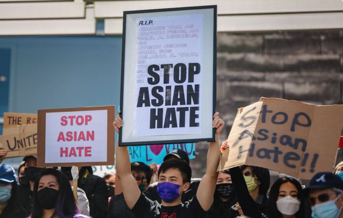 Three protesters hold up Stop Asian Hate signs