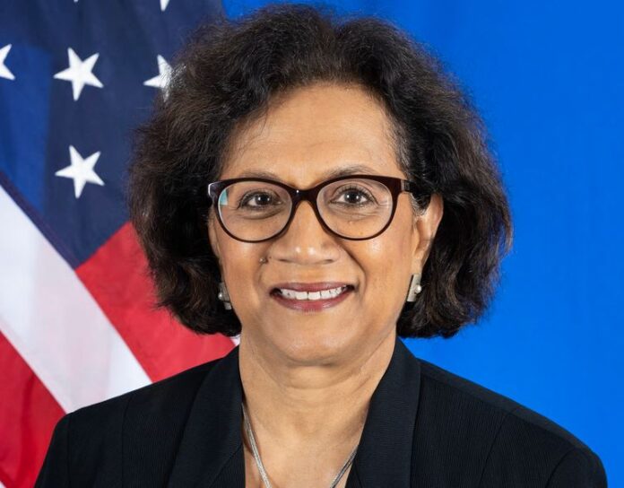 photo of Geeta Rao Gupta in front of the U.S. flag