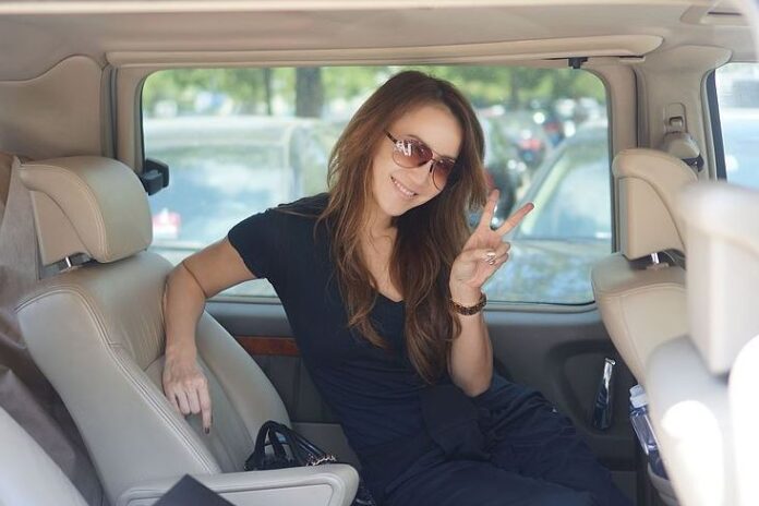 CoCo Lee gives the victory symbol while appearing to be sitting in the back seat of a car