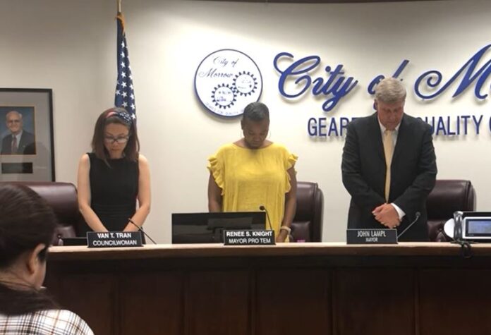 Van Tran, seen on the left, bows her head in a brief moment of silent prayer after the Pledge of Allegiance at the Morrow City Council meeting in Georgia near Atlanta