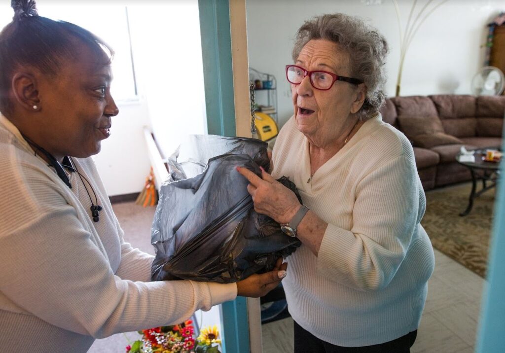 A senior citizen receives a bag of food from Food Rescue 