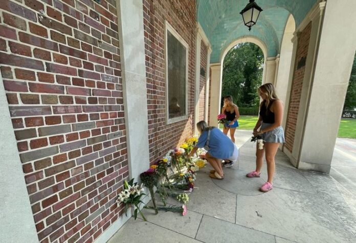 Two mourners place flowers at a makeshift memorial for Professor Zijie Yang at the University of North Carolina, Chaple Hill