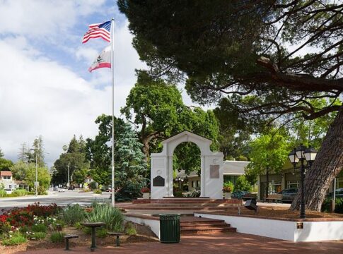 Saratoga, CA memorial Arch with the U.S. and California state flags flying.