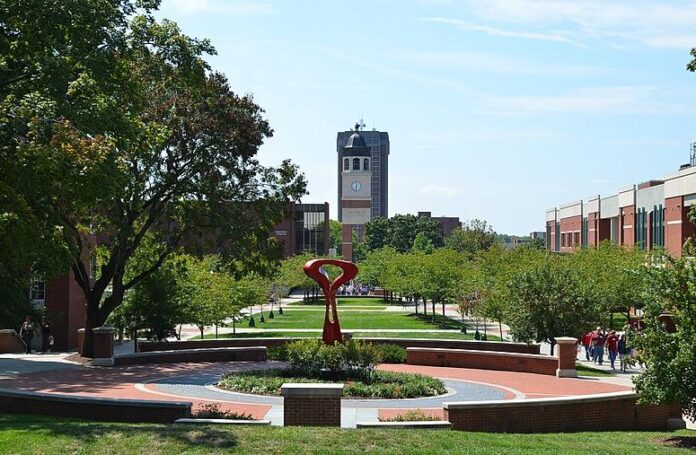 Western Kentucky University with a sculpture in the foreground and clock tower in the background with grassy field in between