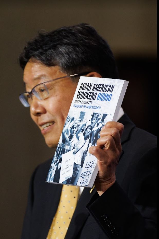 While making opening statements at the induction ceremony, Kent Wong, Director of the UCLA Labor Center, holds up a book commemorating solidarity demonstrations that he mobilized while in New York City convening with the Asian Pacific American Labor Alliance, AFL-CIO as the organization's elected founding president when the news of El Monte broke.