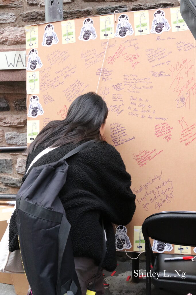 Young woman leaves a note on the large board with note for Corky Lee. Photo by: Shirley L. Ng
