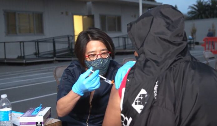 A doctor injects a COVID vaccination into the arm of a patient