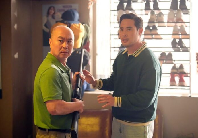 Ben Song as played by Raymond Lee stands next to a man with a rifle during the Koreatown riots