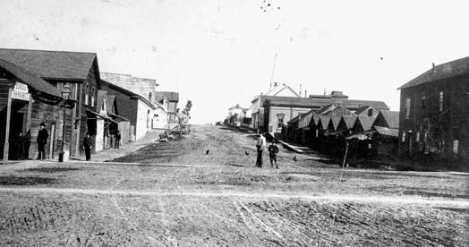 1885 photo of Fourth and E streets in Eureka looking east. Chinatown is on the right and the first few buildings on the left. Eureka City Councilman David Kendall was accidentally shot at this crossing. 中文：1885Eureka。唐人街位于照片右边和左边前几栋房子。David Kendal在这个十字路口被意外射死。