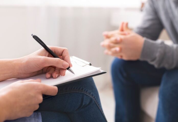A therapist takes notes during her session with a patient