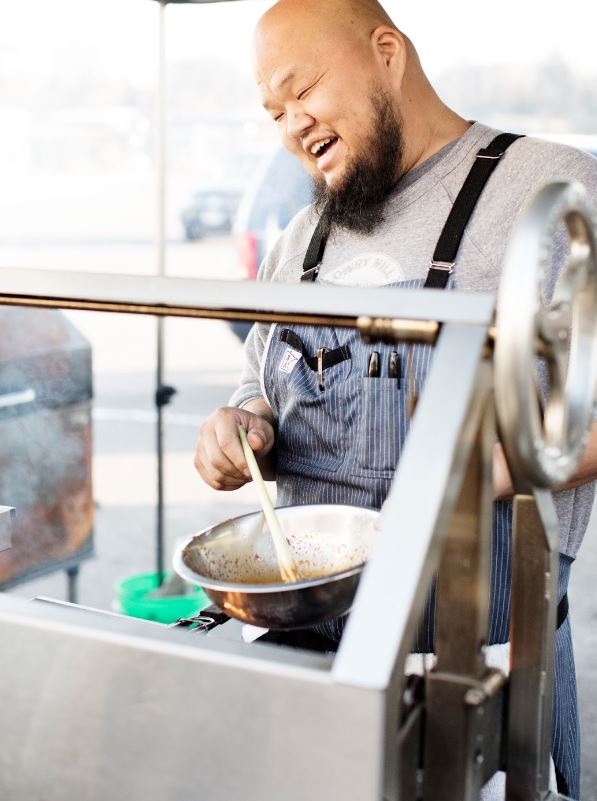 Yia Vang smiles broadly as he mixes his ingredients in a bowl