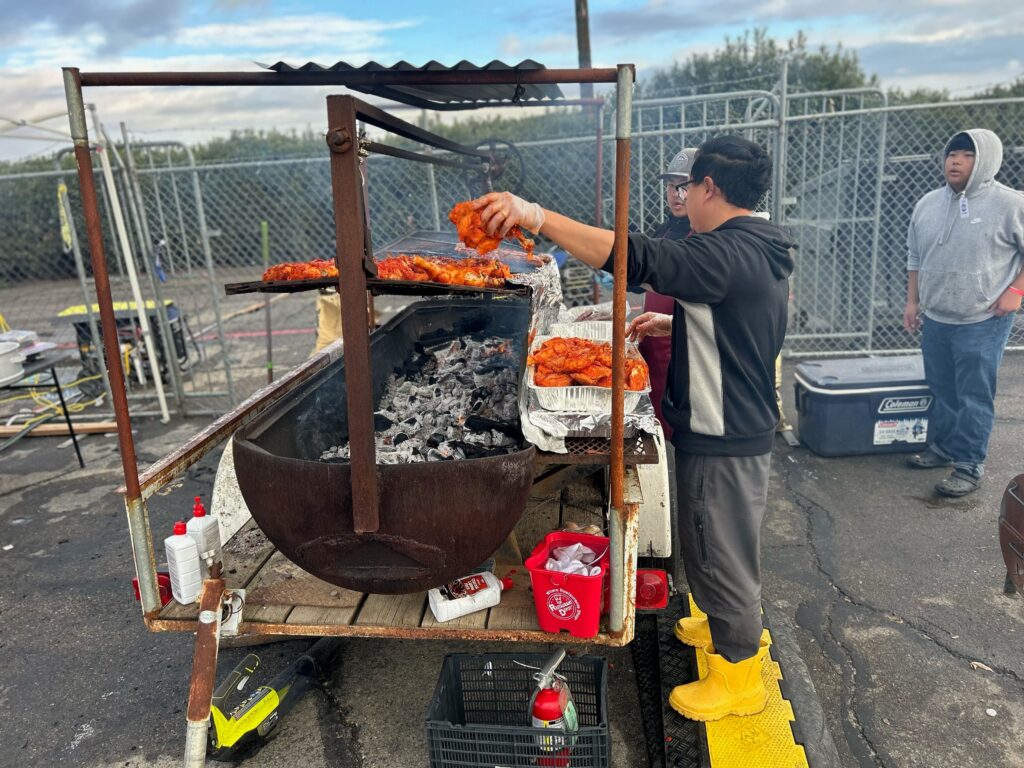 A worker of The Hungry Hippo of Fresno grilling chicken and sausages at the Hmong Cultural New Year Celebration. Photo by Jia H. Jung