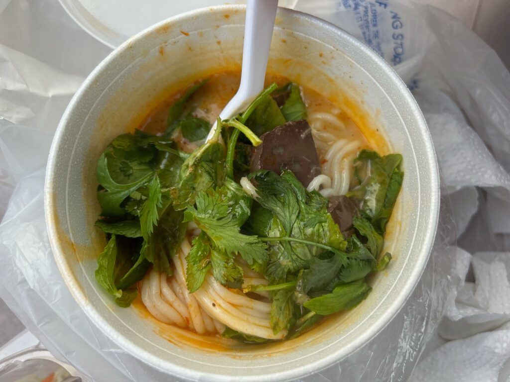 Khao poon red curry noodles with cubes of pork blood curd and plenty of cilantro at the Hmong Cultural New Year Celebration. Photo by Jia H. Jung