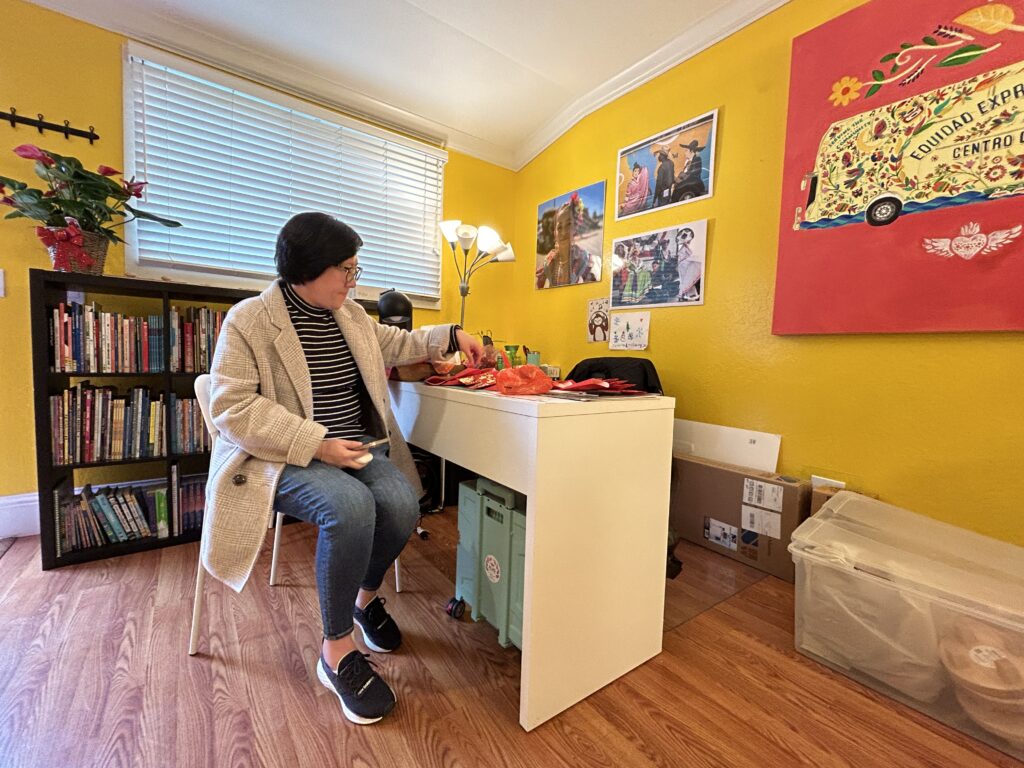 Sao Leng U organizes red and gold funereal envelopes, stuffed with the blessings of a hard candy and a one dollar bill. at Ayudando Latinos a Soñar (ALAS) Casita and Garden in Half Moon Bay before the Corazón del Campesino Memorial Evening commemorating the mushroom farm shootings on Jan. 23