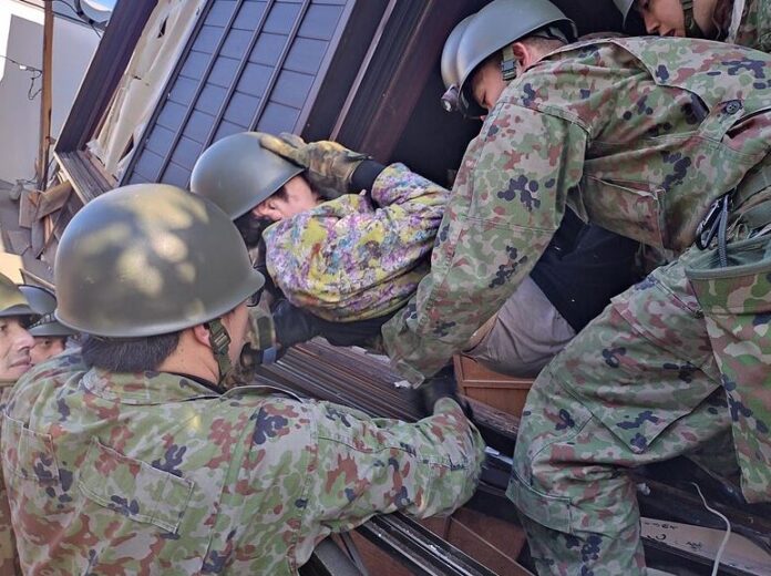 Members of the Ground Self Defense Force 10th Division rescue a quake survivor under a collapsed house