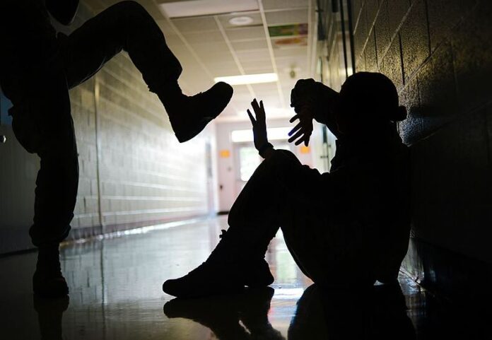 Shadow of student sitting in front of a locker being kicked by an unidentified person