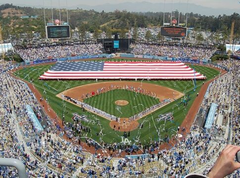 A capacity crowd at Dodger Stadium during the National Anthem as a large American flag is held in the outfield