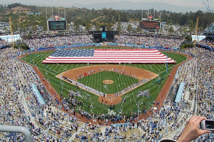 A capacity crowd at Dodger Stadium during the National Anthem as a large American flag is held in the outfield