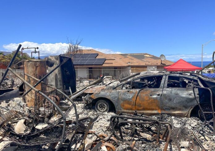 Burned out car sits in front of a destroyed home in Lahaina