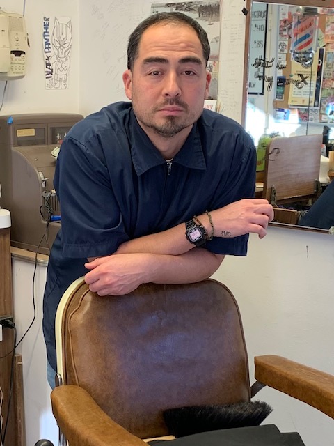 Barber leaning on chair in Nisei Barber Shop.