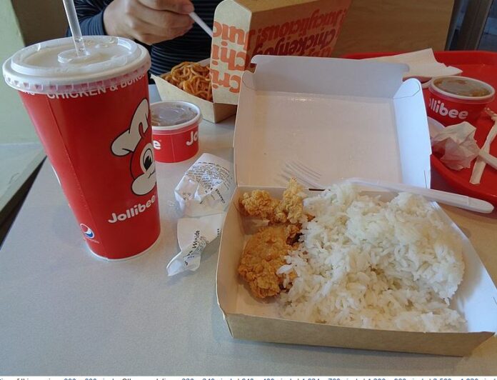 Jollibee fried chicken with rice sitting on a table with a cup of soda nearby