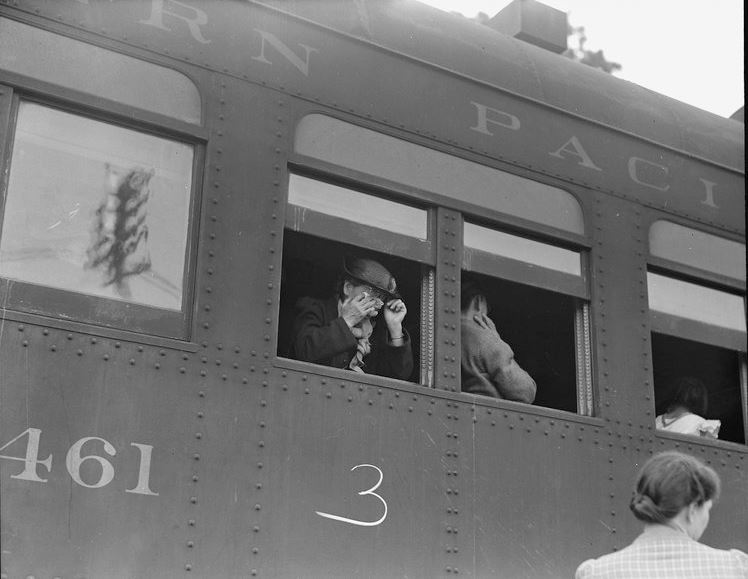 Woodland, Yolo County, California. Ten cars of evacuees of Japanese ancestry are now aboard and the doors are closed. Their Caucasian friends and the staff of the Wartime Civil Control Administration stations are watching the departure from the platform. Evacuees are leaving their homes and ranches, in a rich agricultural district, bound for Merced Assembly Center about 125 miles away.