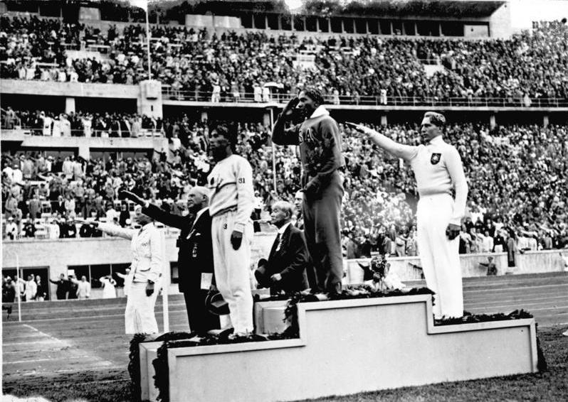 Jesse Owens winning gold for the USA in the long jump of the 1936 Berlin Summer Olympics, alongside Carl Ludwig "Luz" Long, winner of the silver medal for Nazi-controlled Germany and Naoto Tajima, who won bronze for Imperial Japan. Das Bundesarchiv, Bild 183-G00630