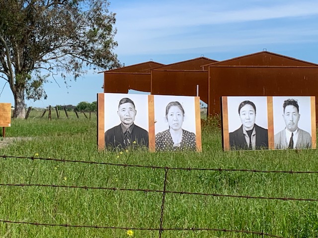 Large photos stand in front of metal sculpture in a field.