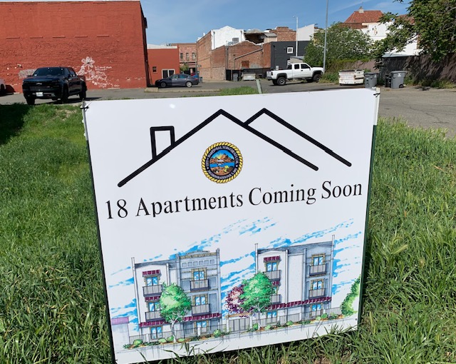 Sign advertises new apartments in vacant lot.