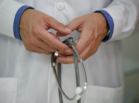 A doctor is seeing holding his stethoscope