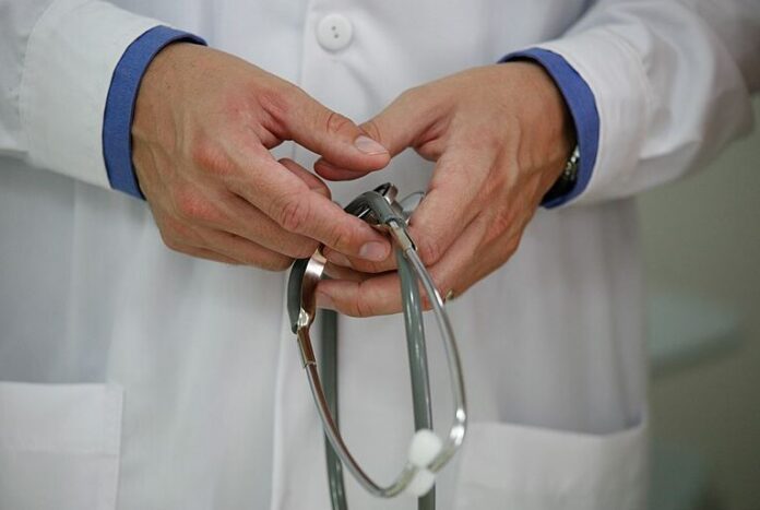 A doctor is seeing holding his stethoscope
