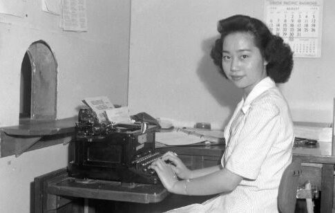 Mitsuye Endo Tsutsumi poses at a typewriter