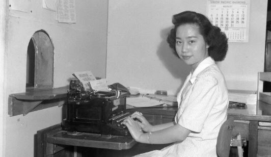 Mitsuye Endo Tsutsumi poses at a typewriter