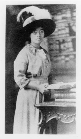 Woman in a featured hat poses with a book.