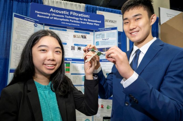 Victoria Ou and Justin Huang, both 17, hold up their small device that they hope will someday filter microplastics from ocean water.