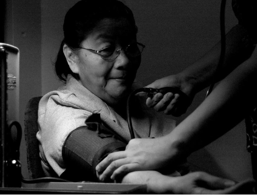 Asian woman gets her blood pressure taken by a nurse